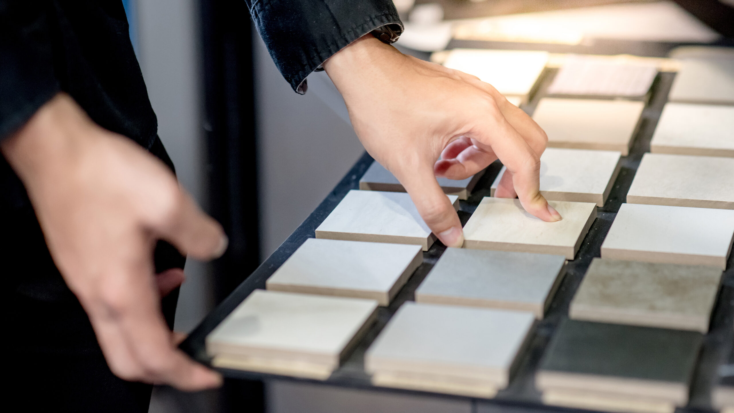 Choosing ceramic sample from swatch board person selecting tiles